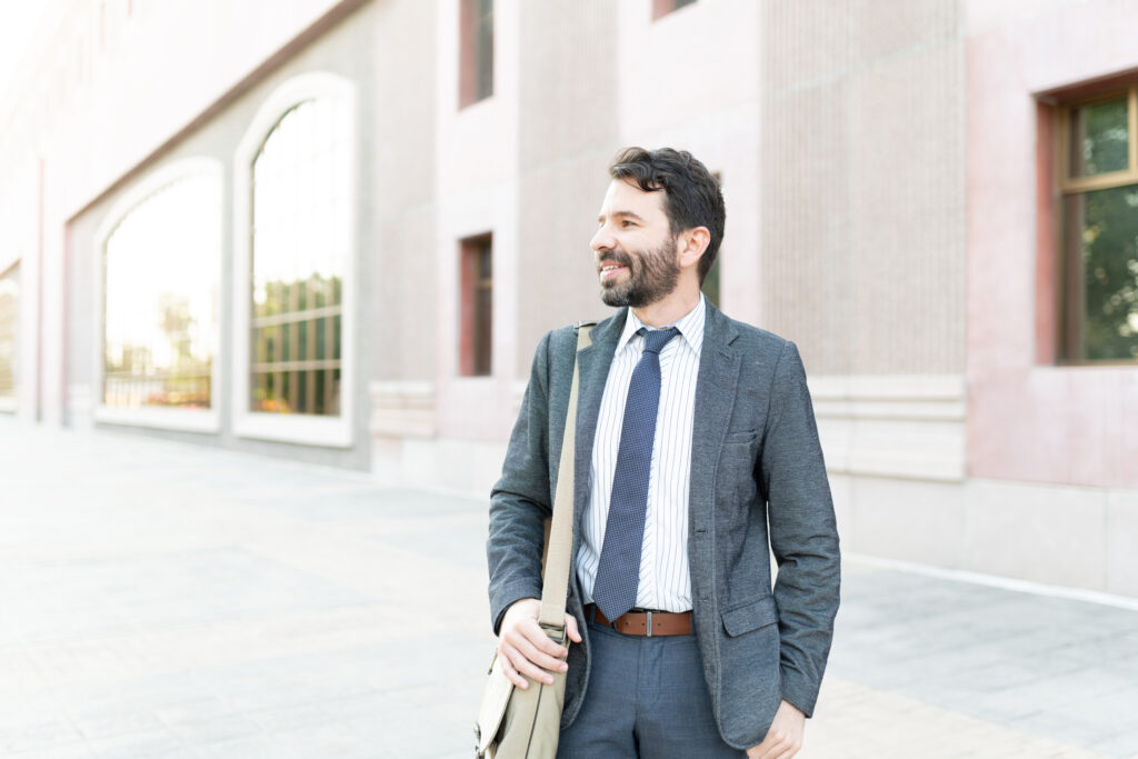 Hispanic male worker arriving at his work building. Adult man commuting to work by walking