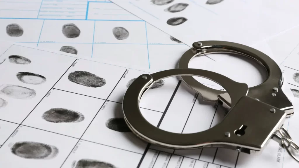 Handcuffs on fingerprint sheet symbolizing criminal investigation and law enforcement.
